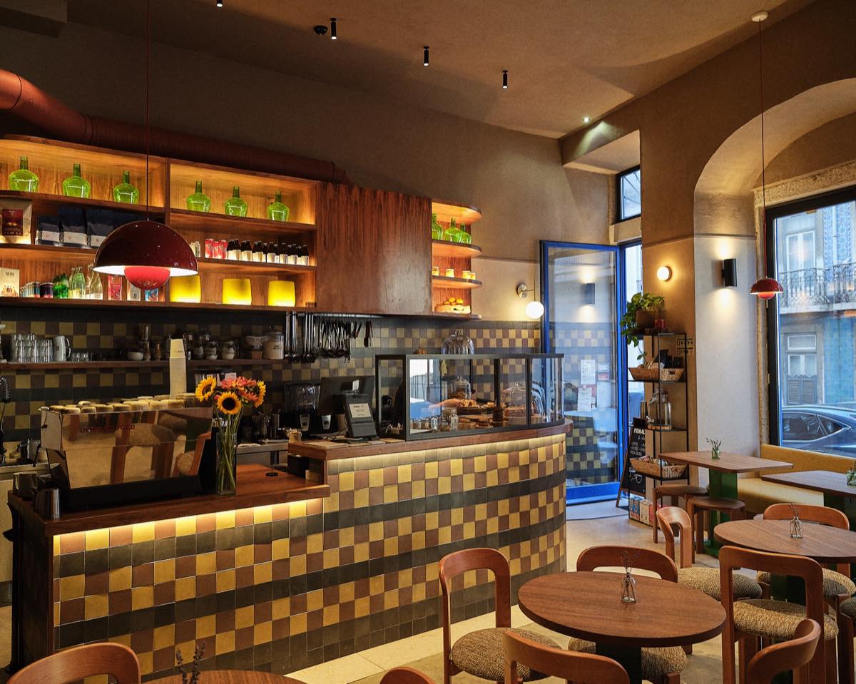The caf&eacute; with nobody in it: the tiled counter and round wooden tables